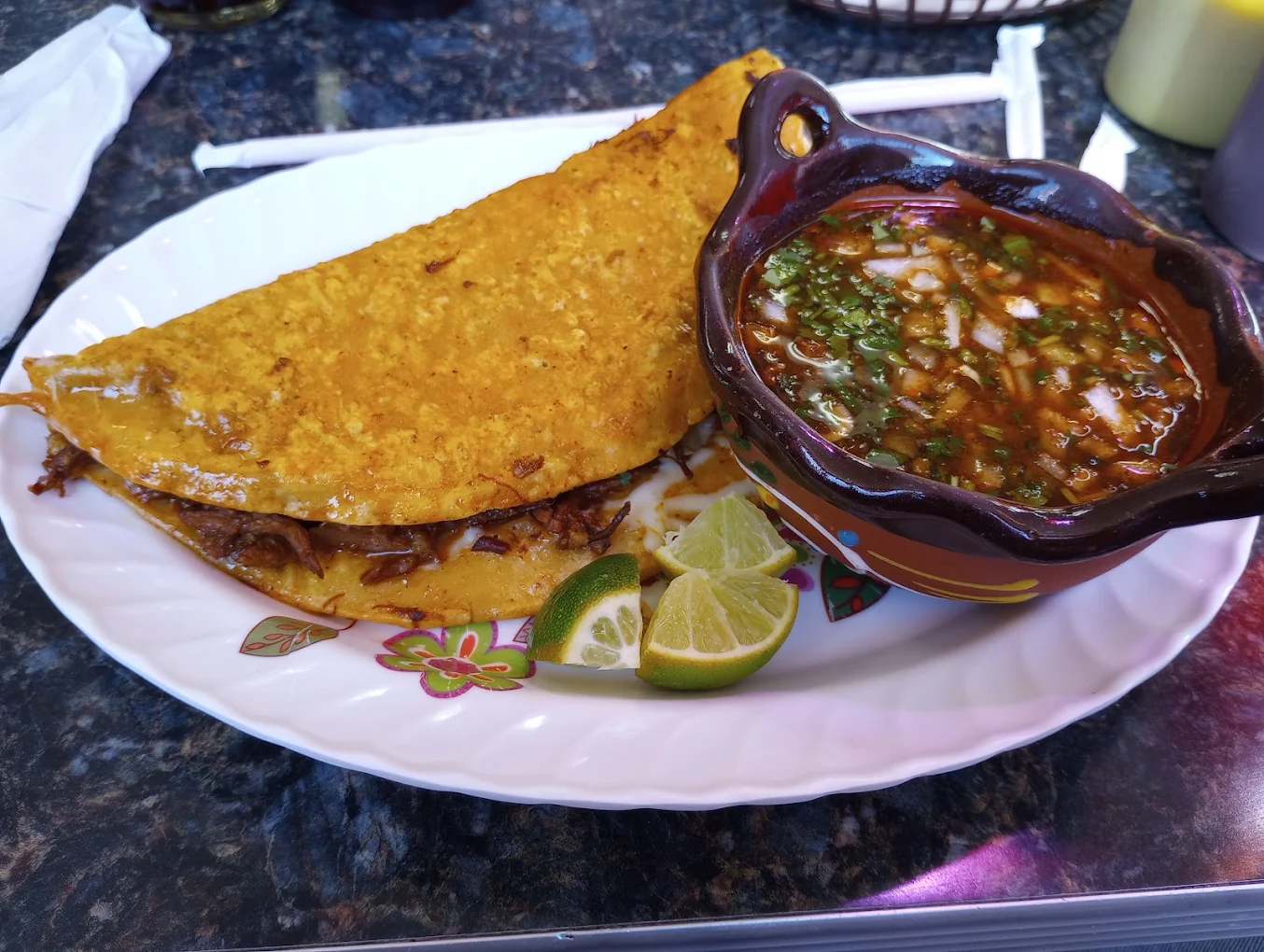 Folded birria taco served with salsa and lime