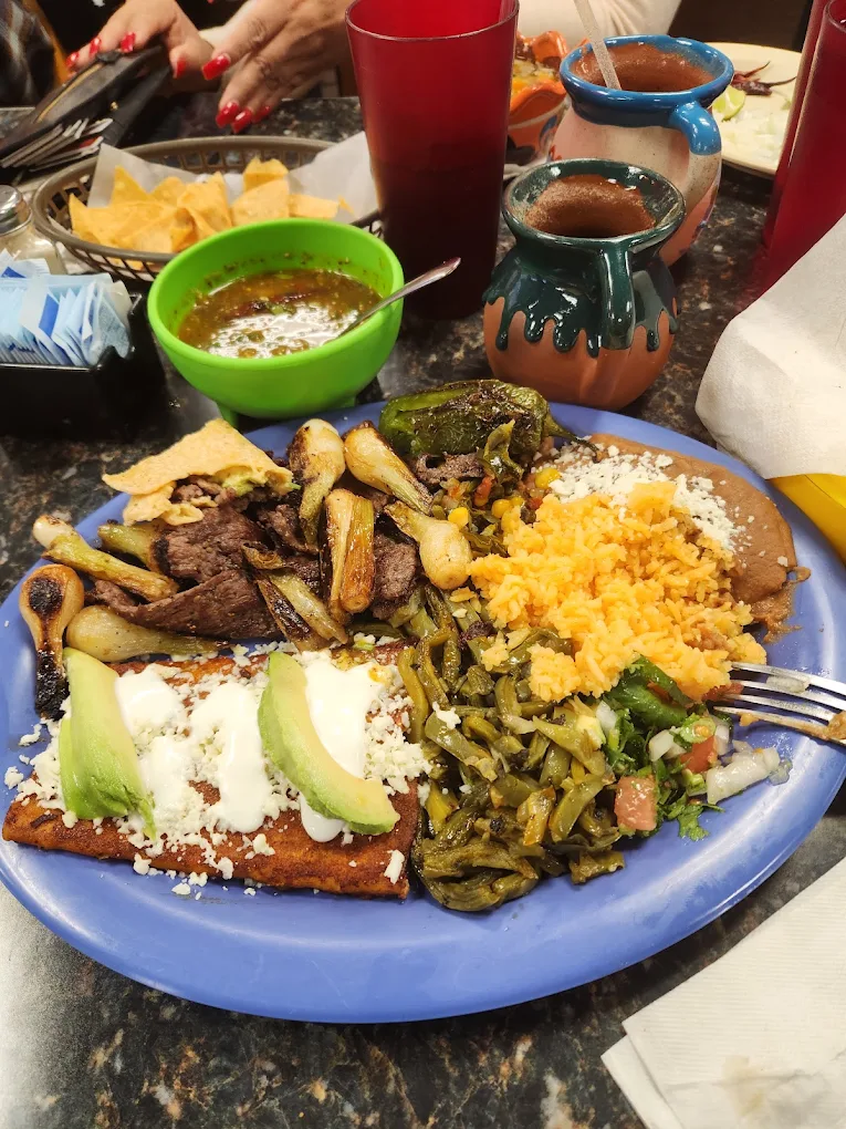 Generous Mexican house plate with grilled meat, rice, beans, nopales and avocado